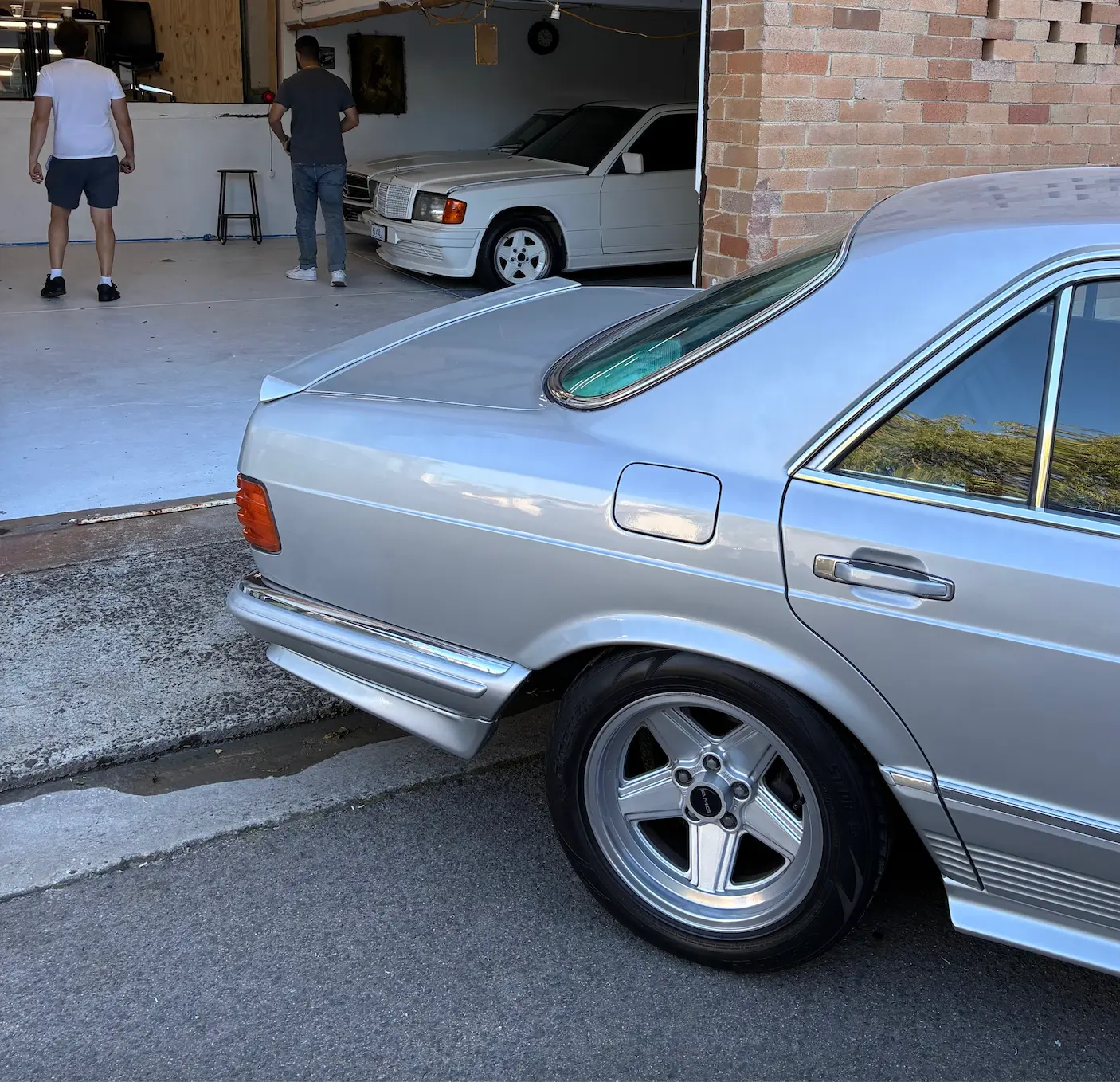 Silver Mercedes 500 SEC AMG parked outside an enthusiast workshop